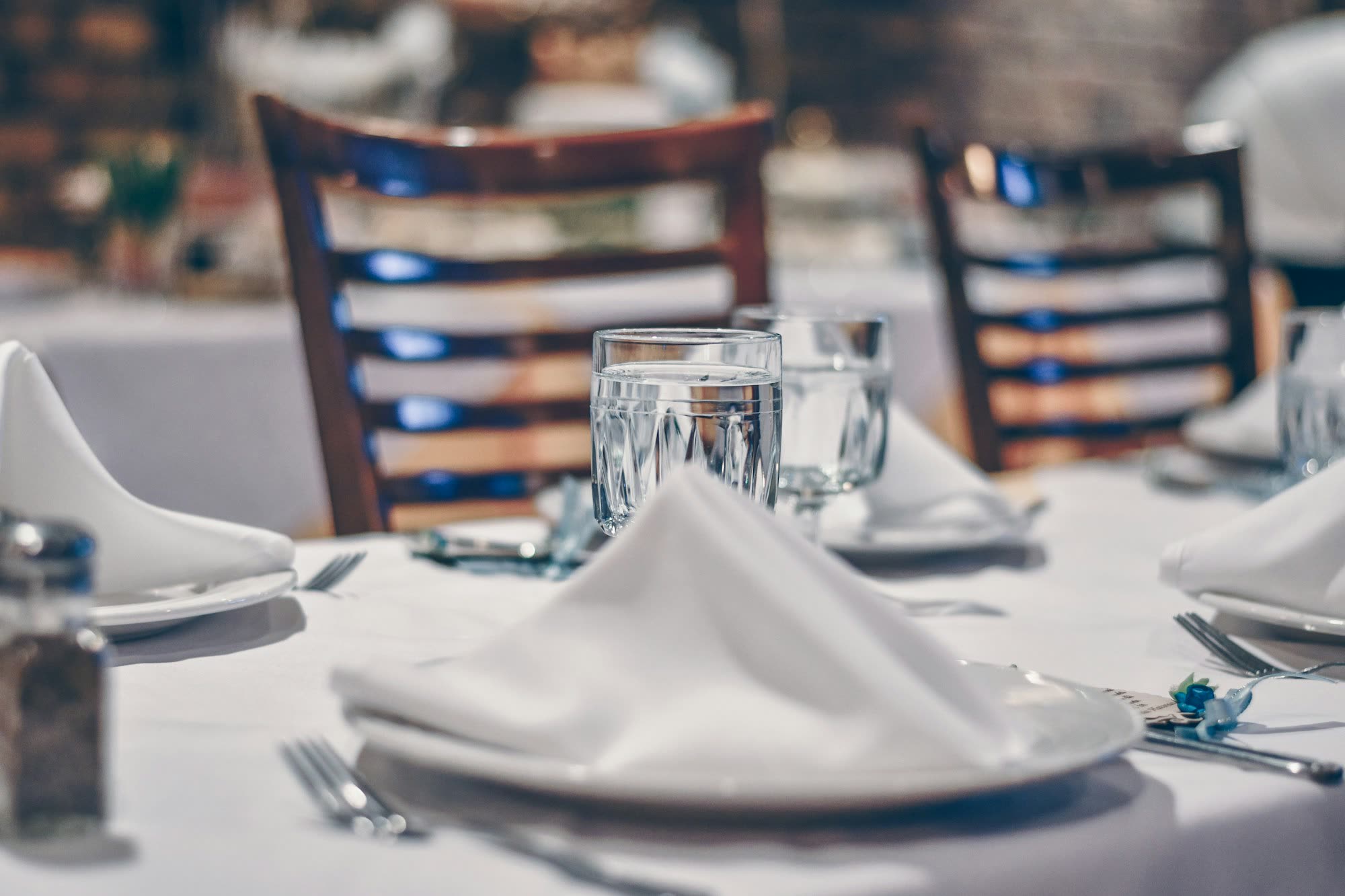 A folded napkin on a plate beside a water glass at a set table, generic stock photo pending real venue photography.