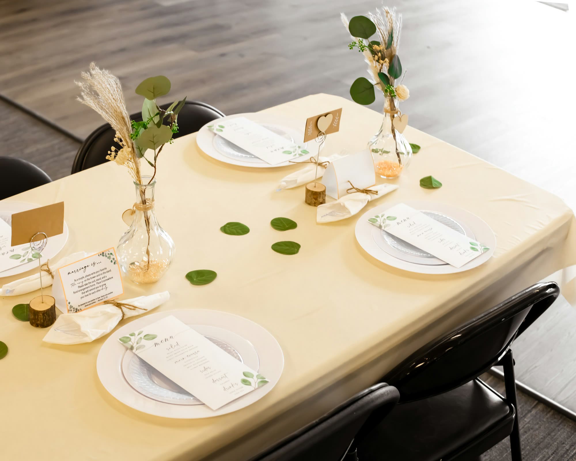 Place settings with menu cards and small bud vases on a cream tablecloth, generic stock photo pending real venue photography.